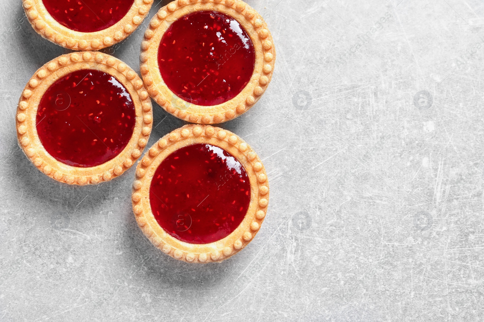 Photo of Tasty tartlets with jam on grey background