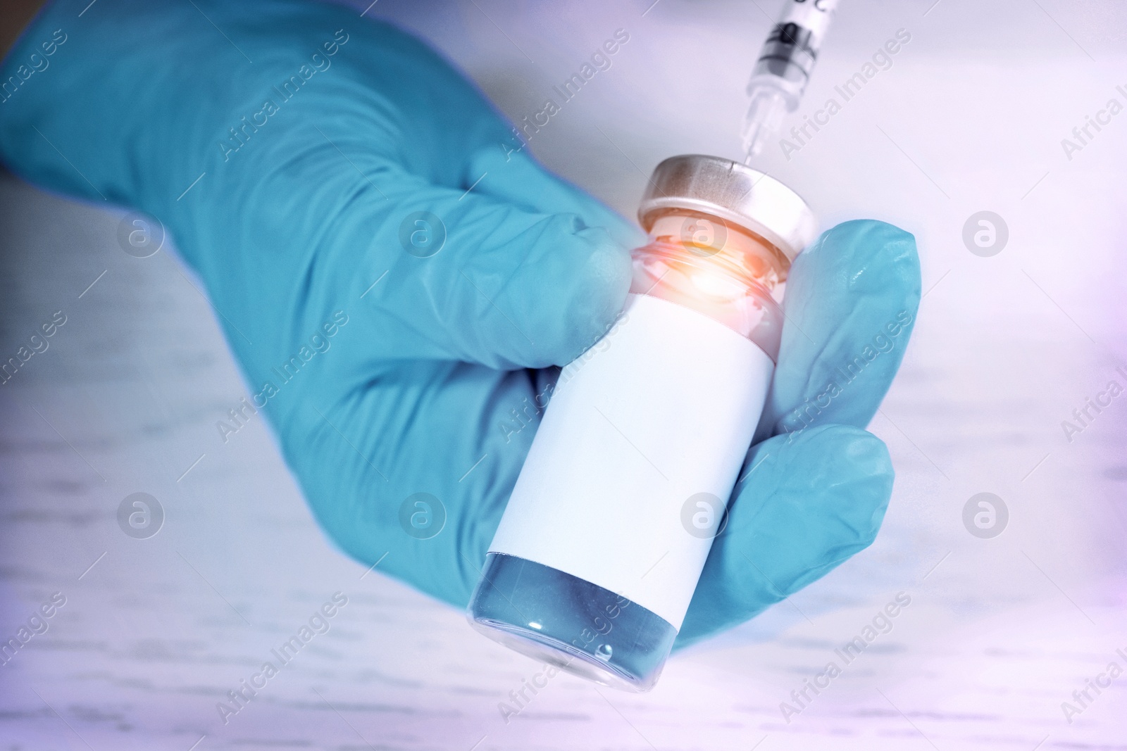 Image of Laboratory worker filling syringe with medication from vial over white wooden table, closeup