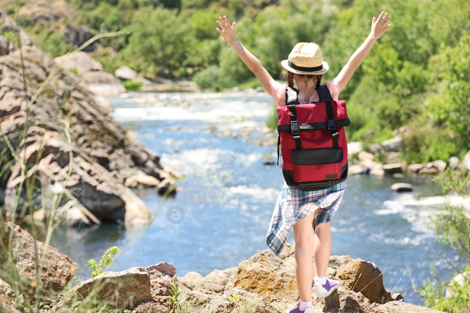 Photo of Little girl on rock near river. Summer camp