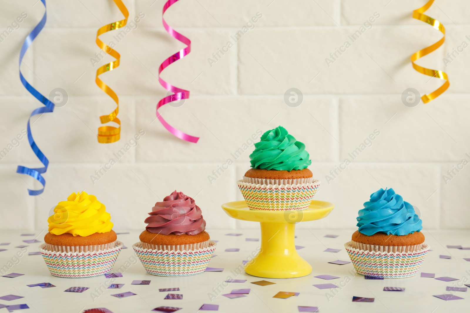 Photo of Delicious cupcakes with colorful cream on white table