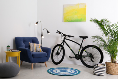 Photo of Modern bicycle and comfortable armchair in stylish living room interior