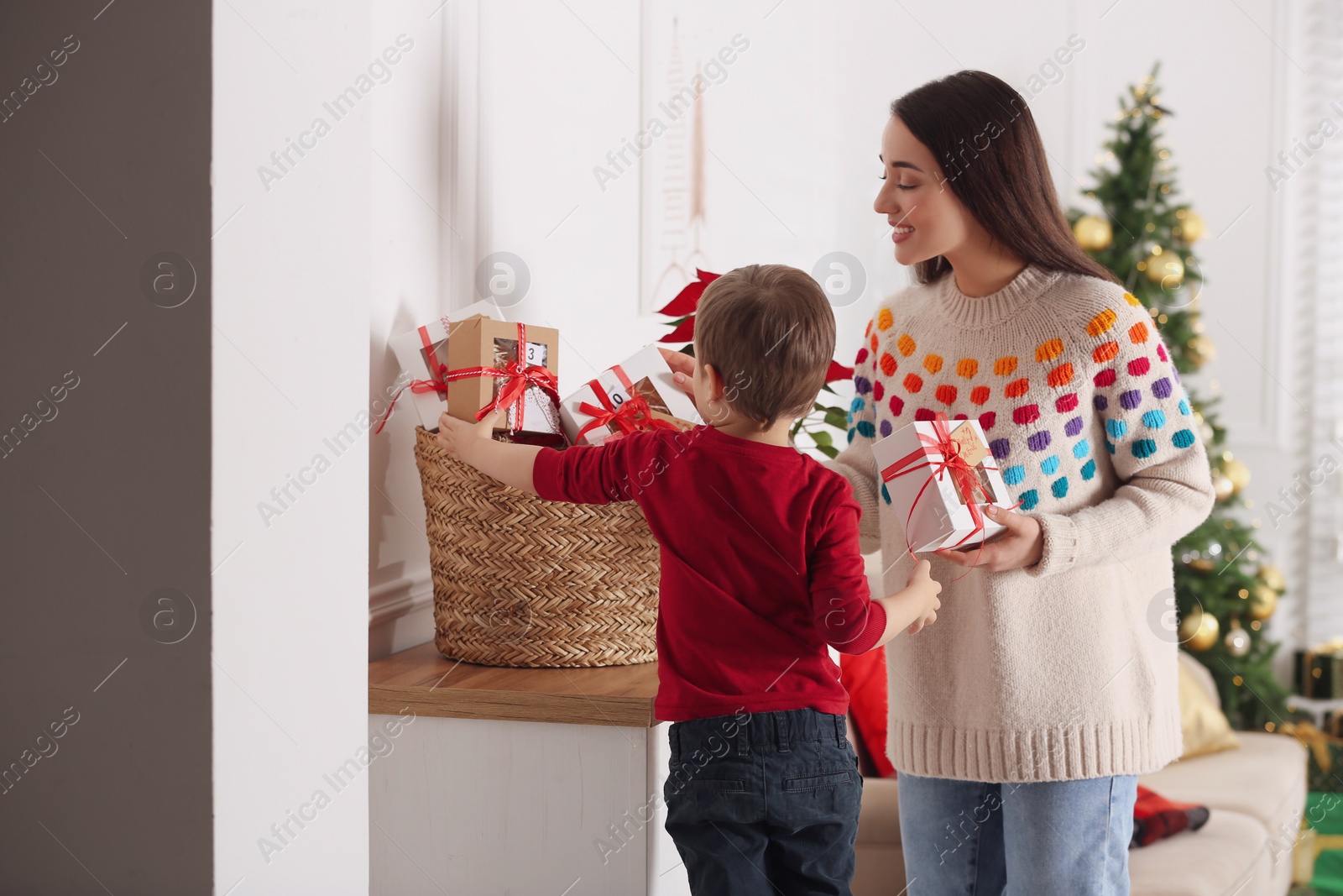 Photo of Mother and son with Christmas gifts at home. Advent calendar in basket