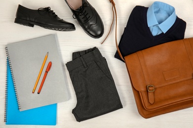 School uniform and stationery on white wooden background, top view