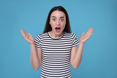 Portrait of surprised woman on light blue background