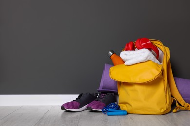 Photo of Backpack and sports equipment on floor near gray wall, space for text