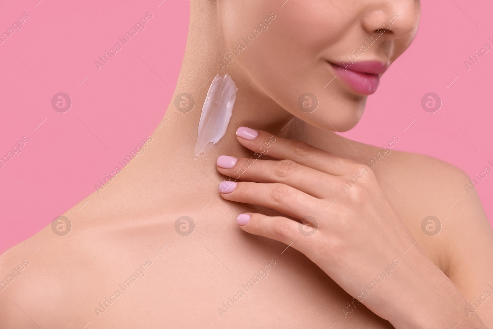 Photo of Woman with smear of body cream on her neck against pink background, closeup