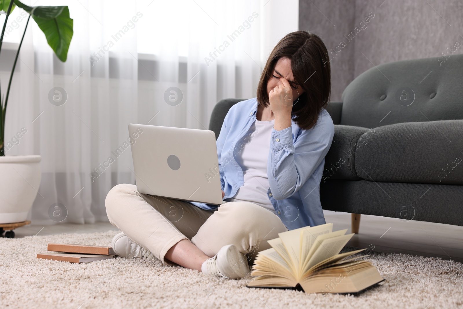 Photo of Overwhelmed woman with laptop sitting on floor indoors