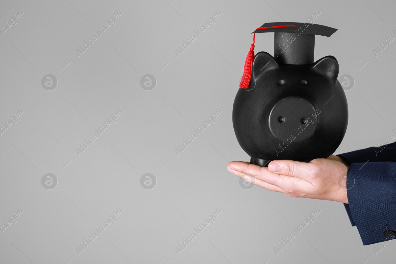 Photo of Woman holding piggy bank and graduation cap against grey background, closeup with space for text. Scholarship concept