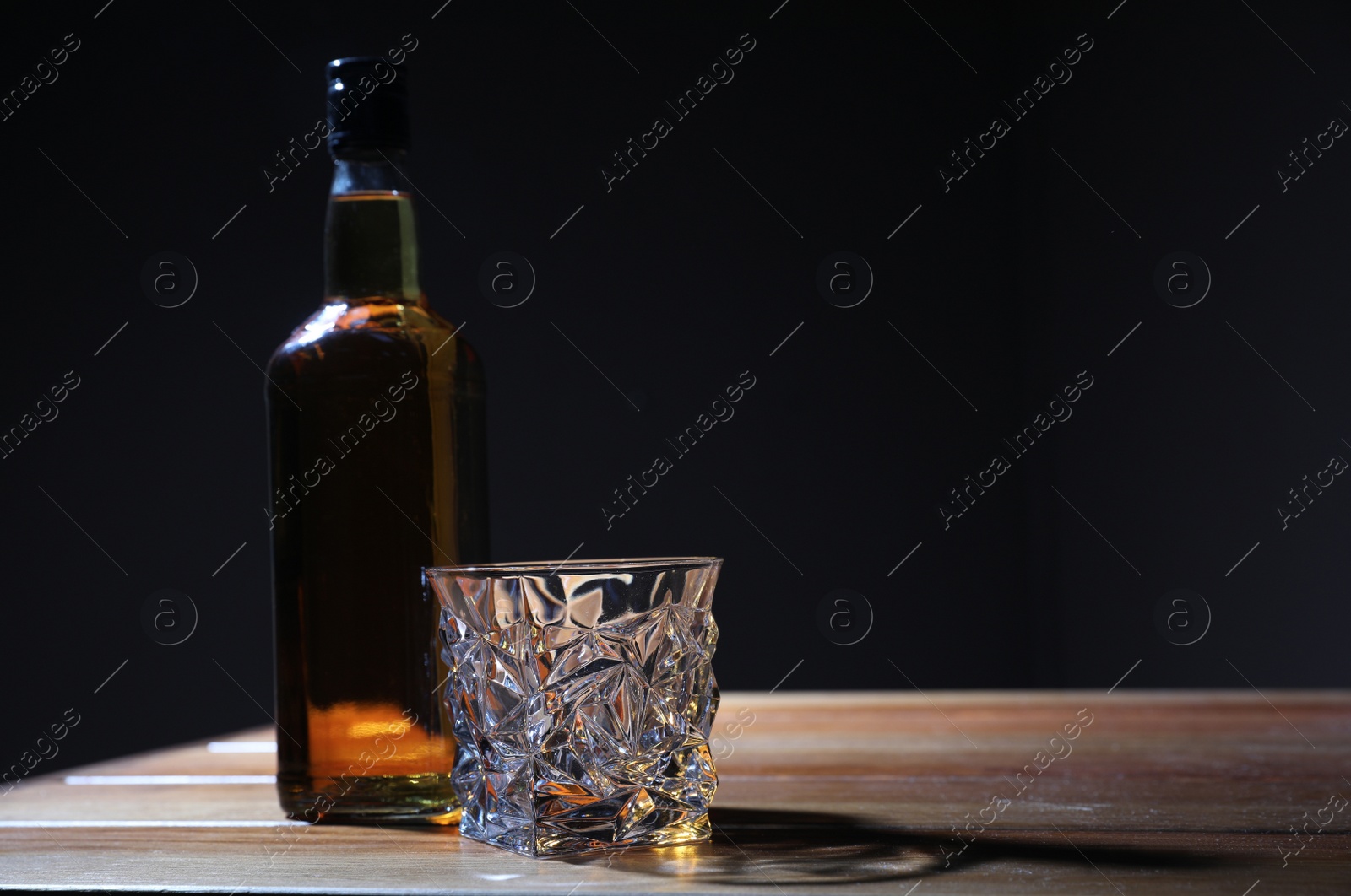 Photo of Whiskey on wooden table against dark background, space for text. Alcohol addiction