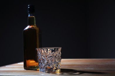 Photo of Whiskey on wooden table against dark background, space for text. Alcohol addiction