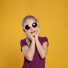 Photo of Smiling girl in stylish sunglasses on orange background