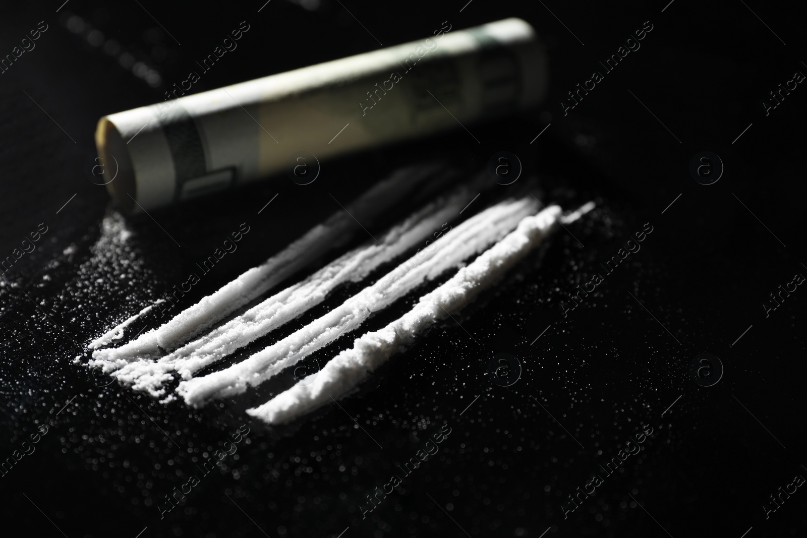 Photo of Drug addiction. Cocaine and rolled dollar banknote on black table, closeup