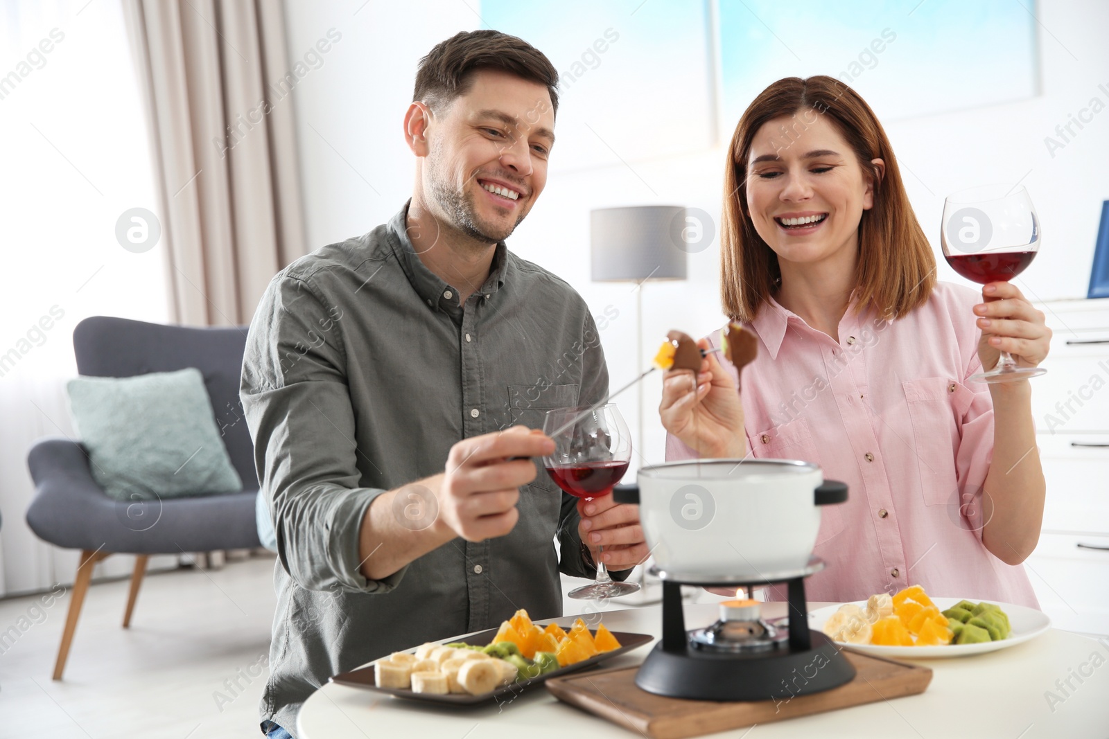 Photo of Happy couple enjoying fondue dinner at home