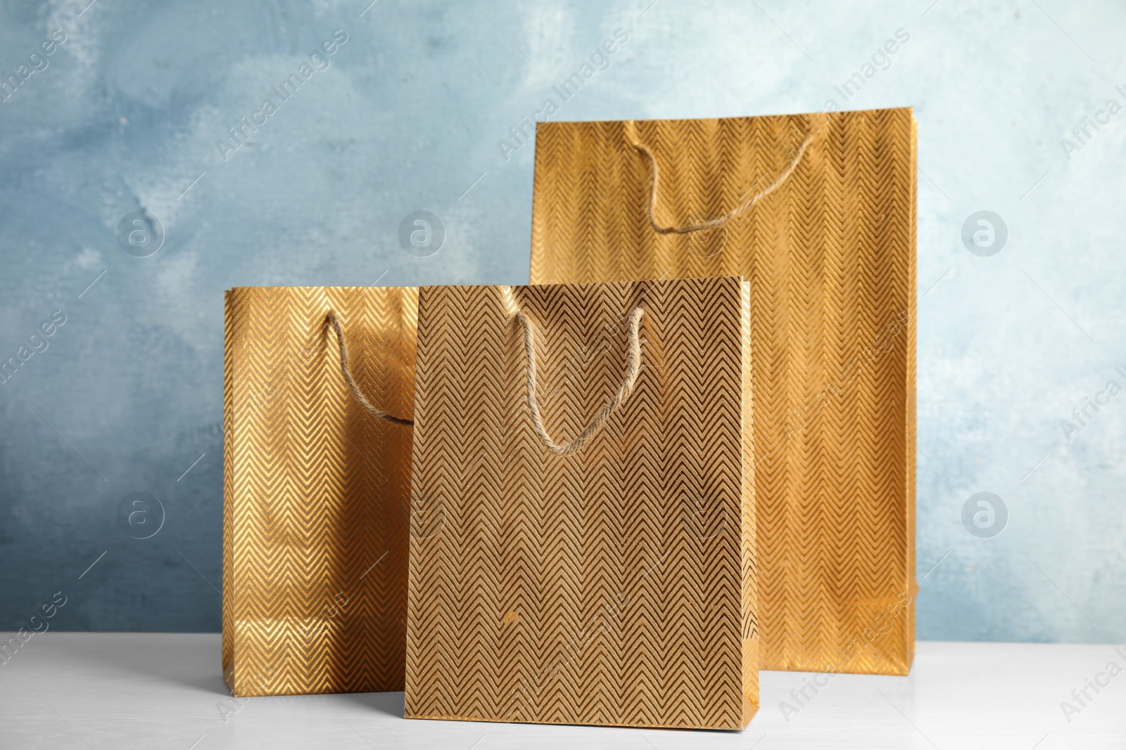 Photo of Gold shopping paper bags on white table