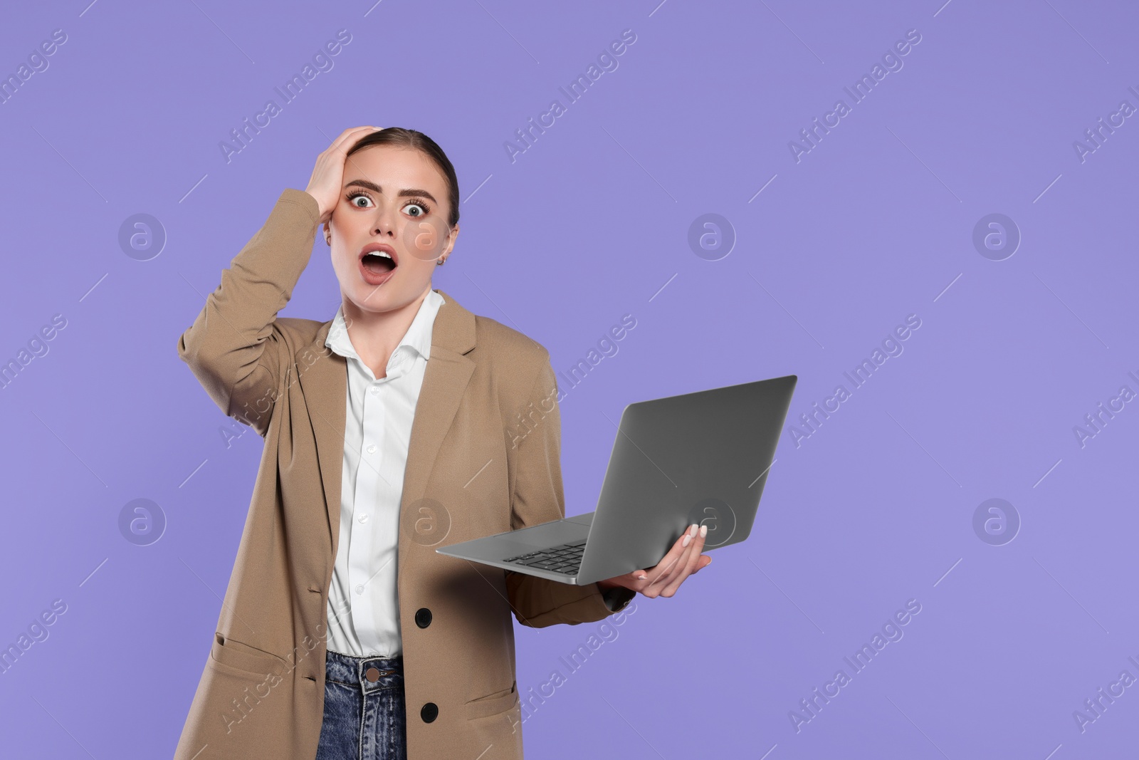 Photo of Emotional woman with laptop on violet background. Space for text