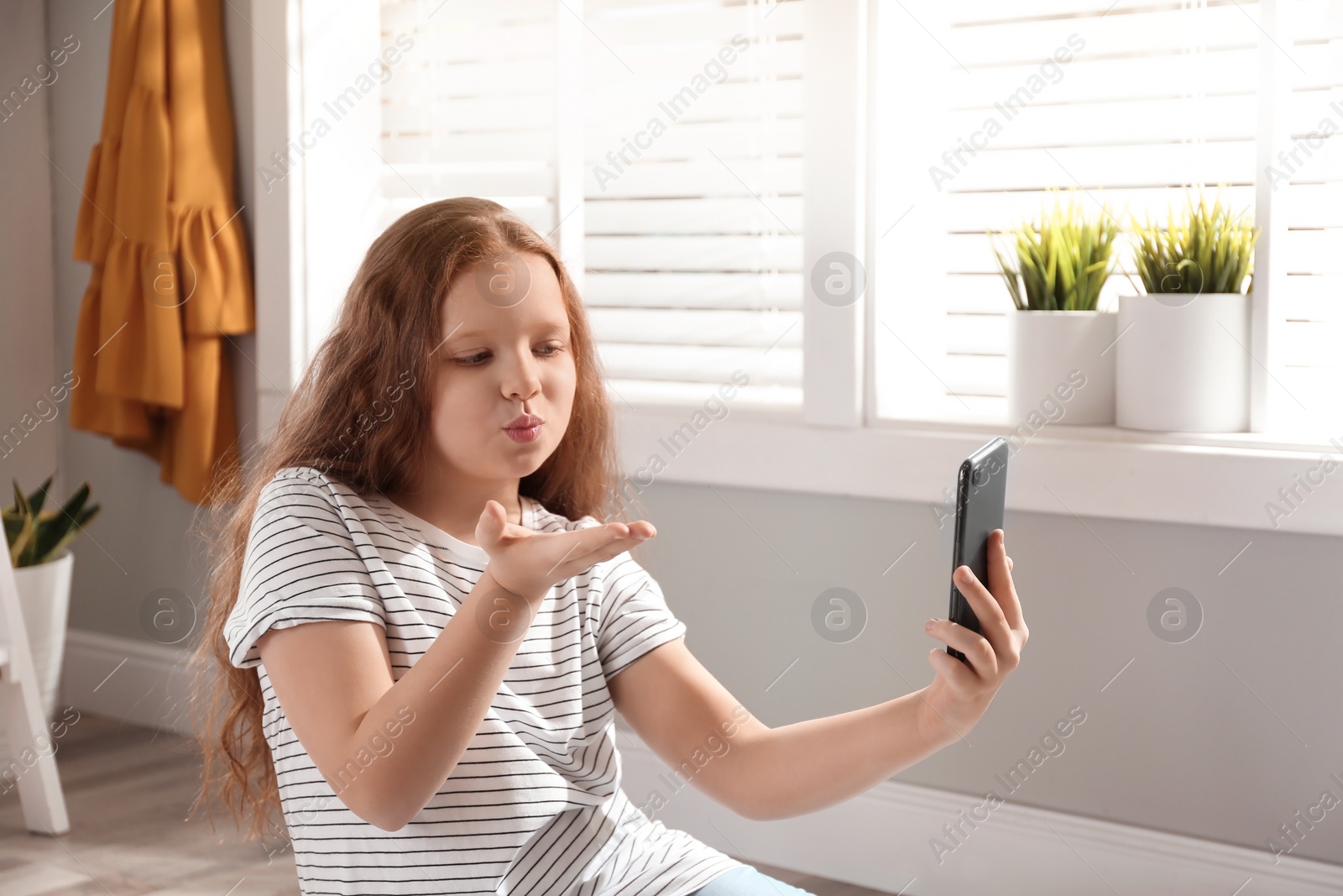 Photo of Cute little girl taking selfie at home