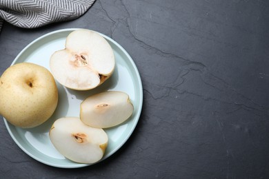 Photo of Cut and whole apple pears on black table, flat lay. Space for text