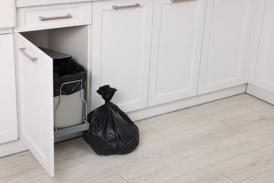 Photo of Plastic garbage bag and trash can in kitchen, space for text