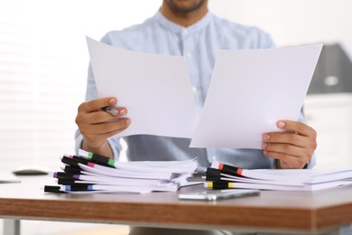 Man working with documents at wooden table in office, closeup