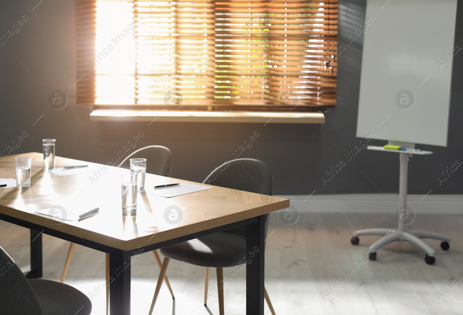 Photo of Stylish office interior with wooden table and flipchart