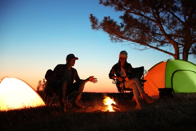 Photo of Couple near bonfire in evening. Camping season