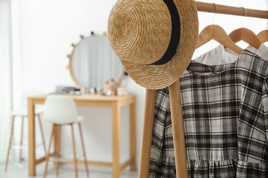 Photo of Hangers with stylish clothes and hat on rack in makeup room. Space for text