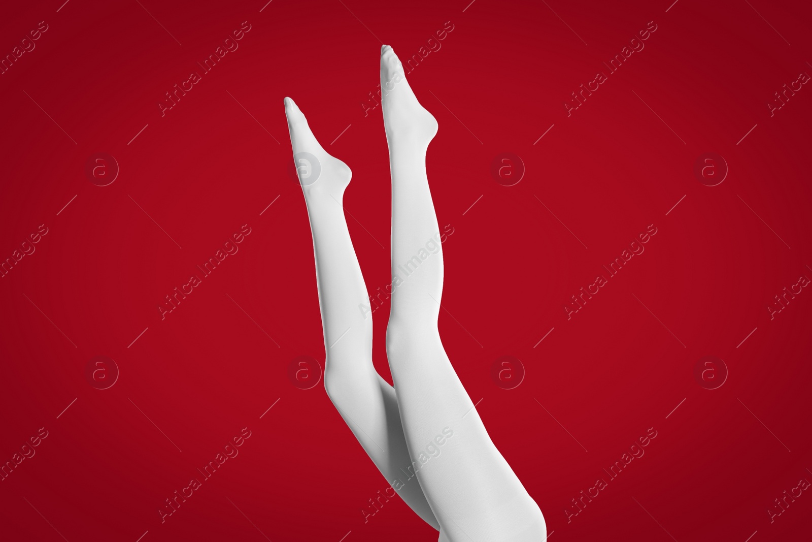 Photo of Woman wearing white tights on red background, closeup of legs