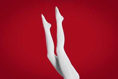 Photo of Woman wearing white tights on red background, closeup of legs