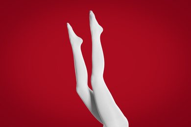 Woman wearing white tights on red background, closeup of legs