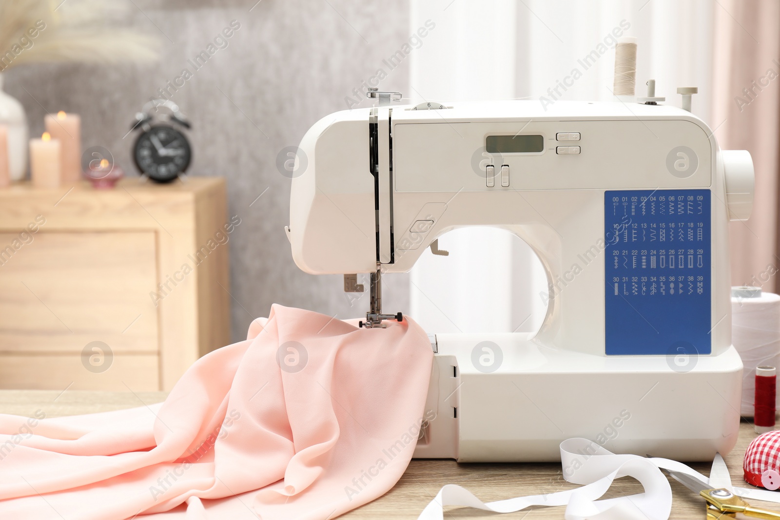 Photo of White sewing machine, cloth and craft accessories on wooden table indoors