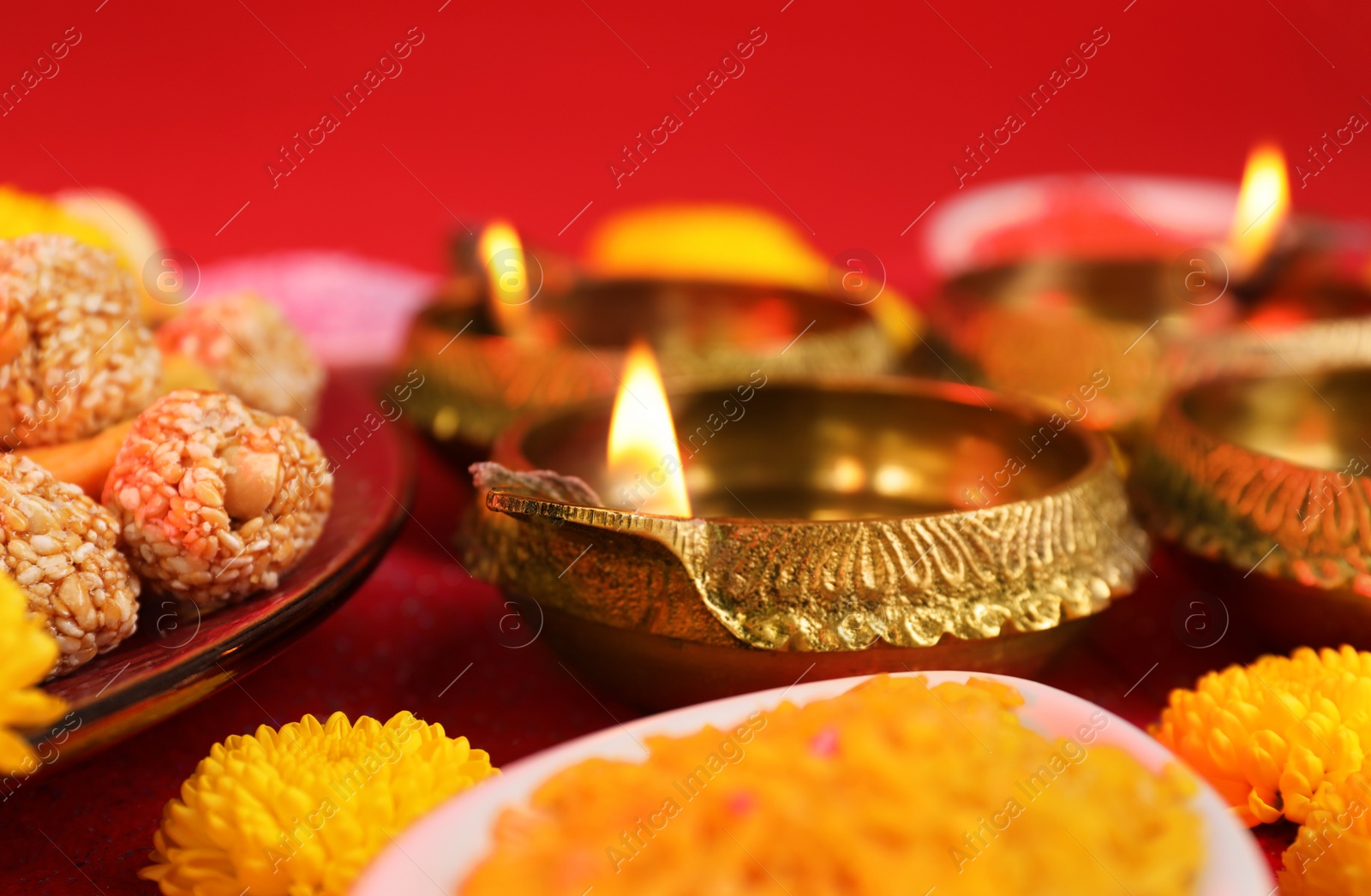 Photo of Diwali celebration. Diya lamps and tasty Indian sweets on table, closeup