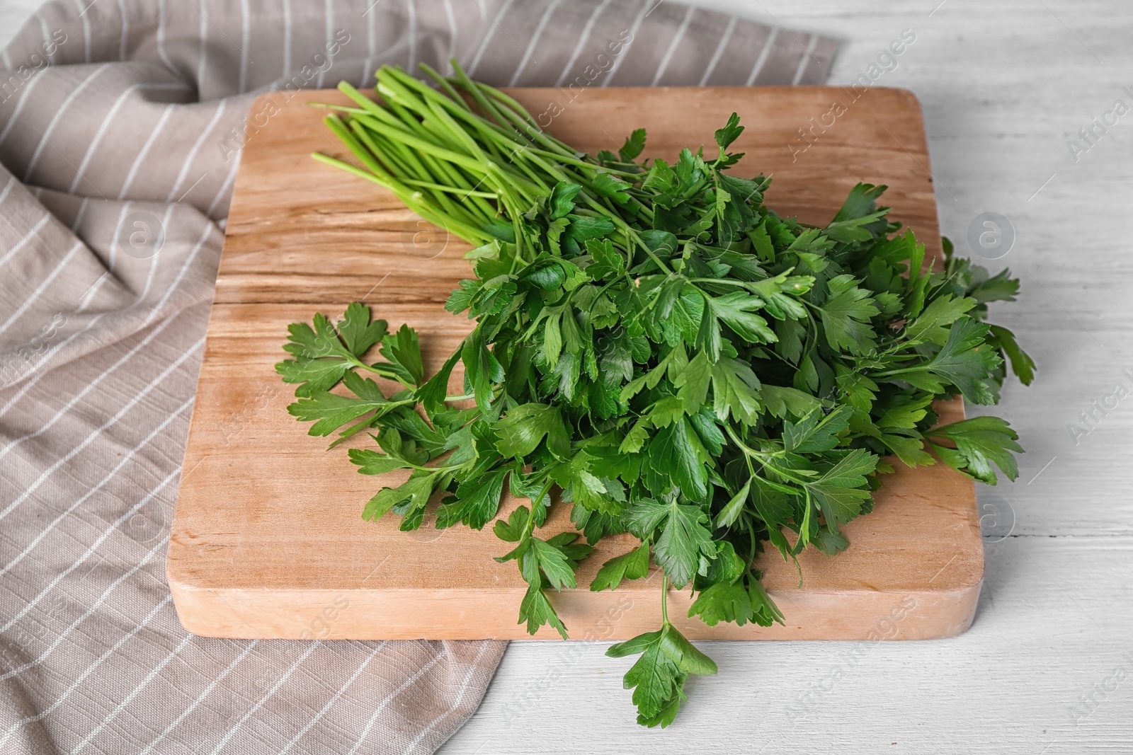 Photo of Wooden board with fresh green parsley on table