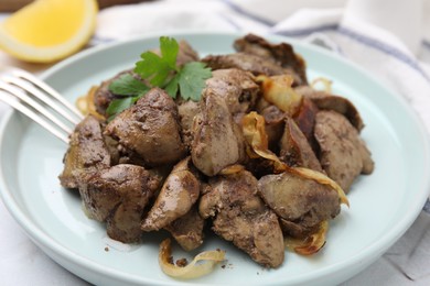 Tasty fried chicken liver with onion and fork on white table, closeup