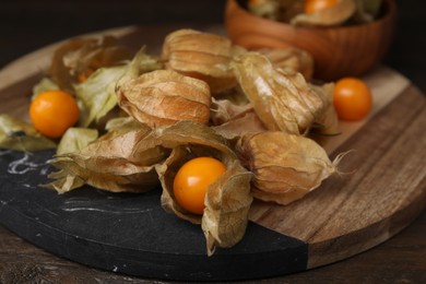 Photo of Ripe physalis fruits with calyxes on wooden table, closeup