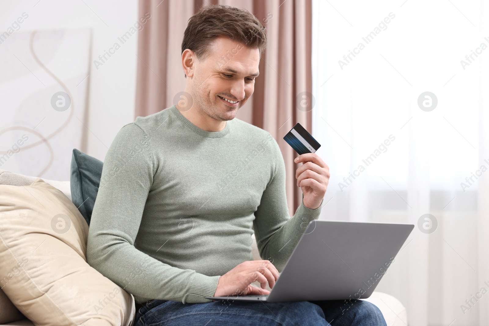 Photo of Man with credit card using laptop for shopping online at home