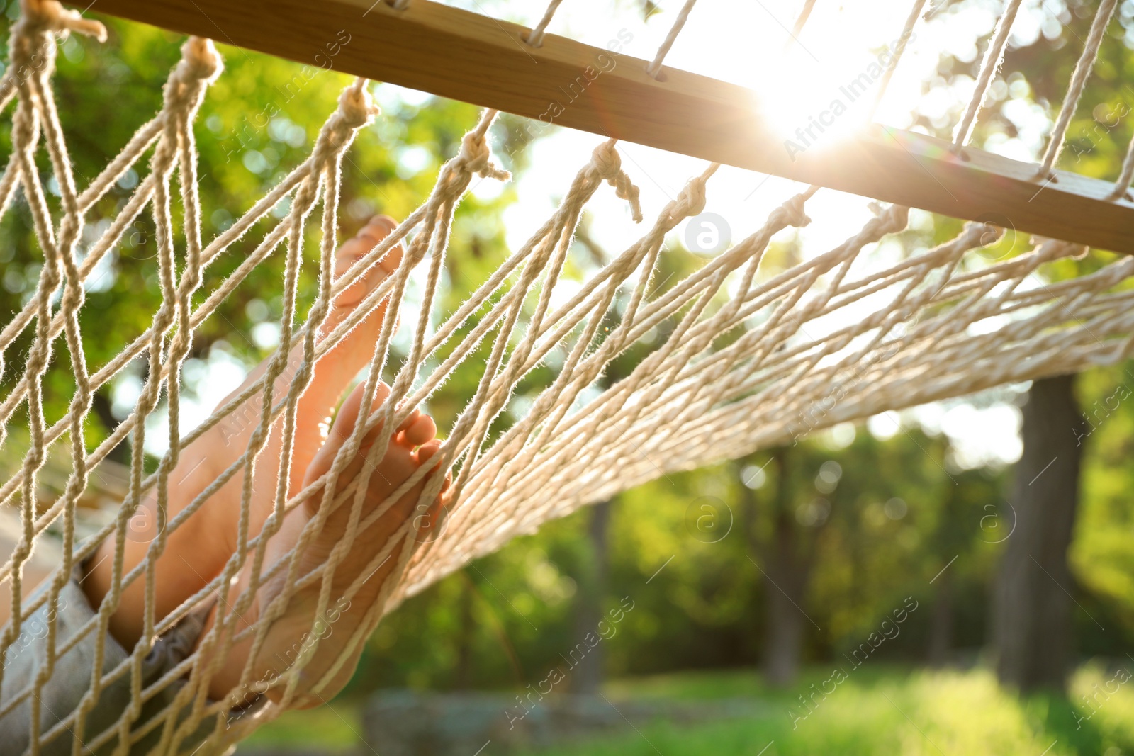 Photo of Young woman resting in comfortable hammock at green garden, closeup