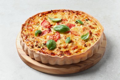 Photo of Tasty quiche with cheese, tomatoes and basil leaves on light grey table