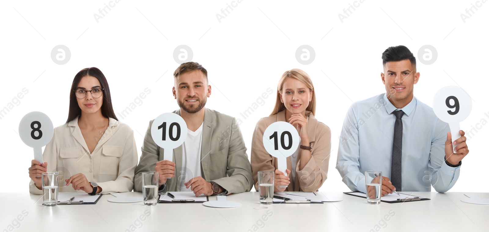 Photo of Panel of judges holding different score signs at table on white background