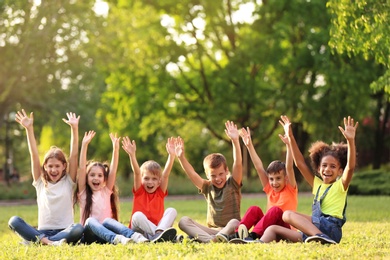 Cute little children sitting on grass outdoors on sunny day