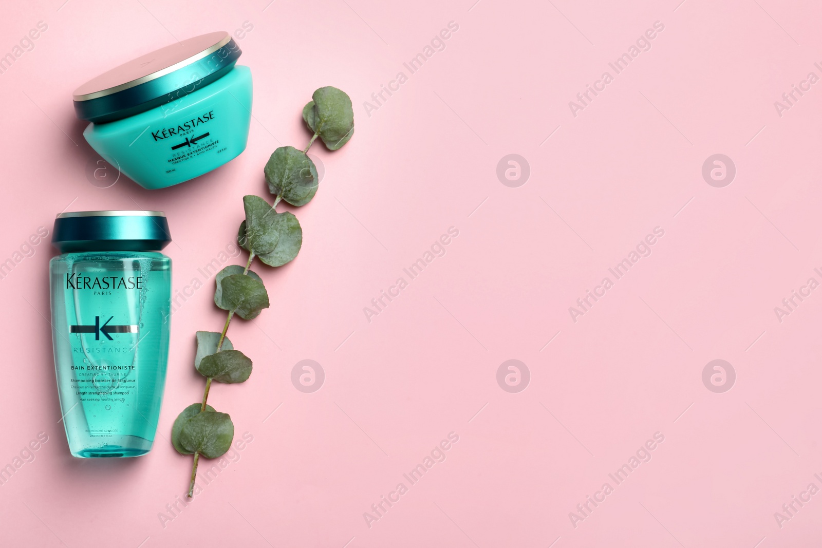 Photo of MYKOLAIV, UKRAINE - SEPTEMBER 07, 2021: Kerastase hair care cosmetic products and eucalyptus on pink background, flat lay. Space for text