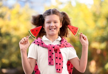 Cute little girl with tasty candies outdoors