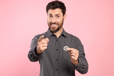 Man holding condom on pink background. Safe sex