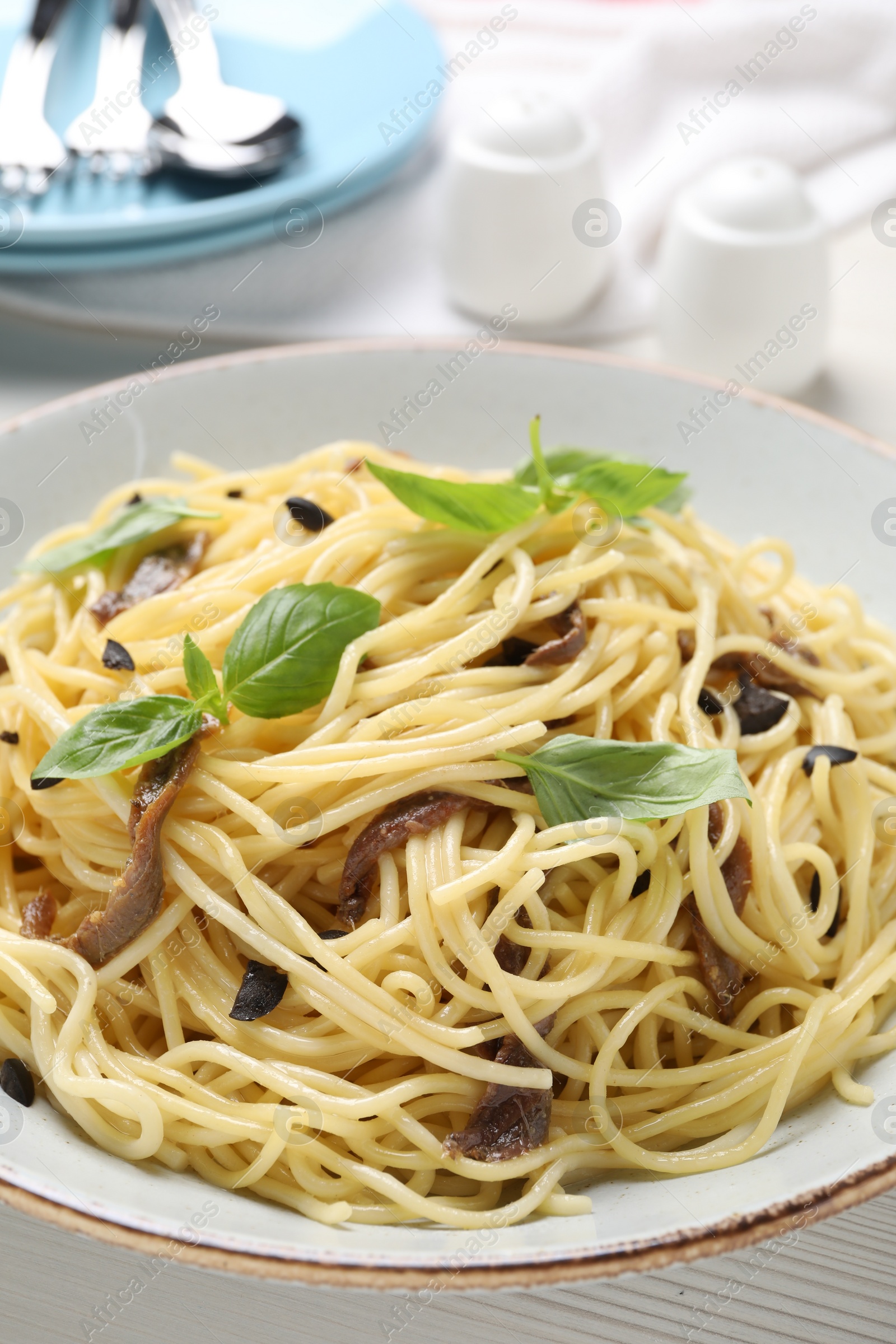 Photo of Delicious pasta with anchovies, olives and basil on plate