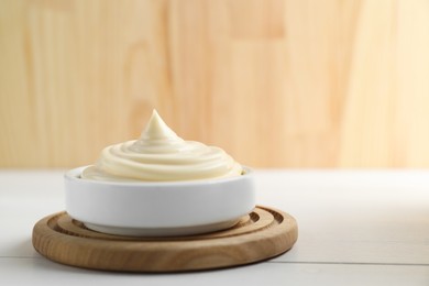 Photo of Fresh mayonnaise sauce in bowl on white wooden table, space for text