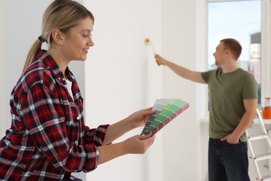Happy woman with paint chips choosing new wall color in apartment during repair