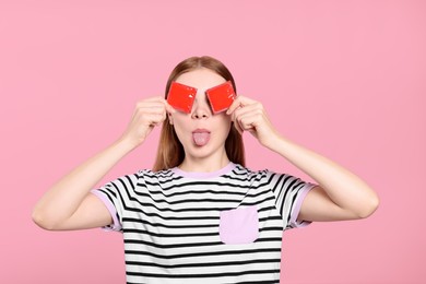 Photo of Woman holding condoms near her eyes on pink background. Safe sex