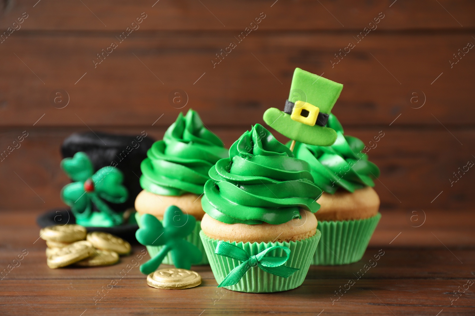 Photo of Decorated cupcakes and coins on wooden table. St. Patrick's Day celebration