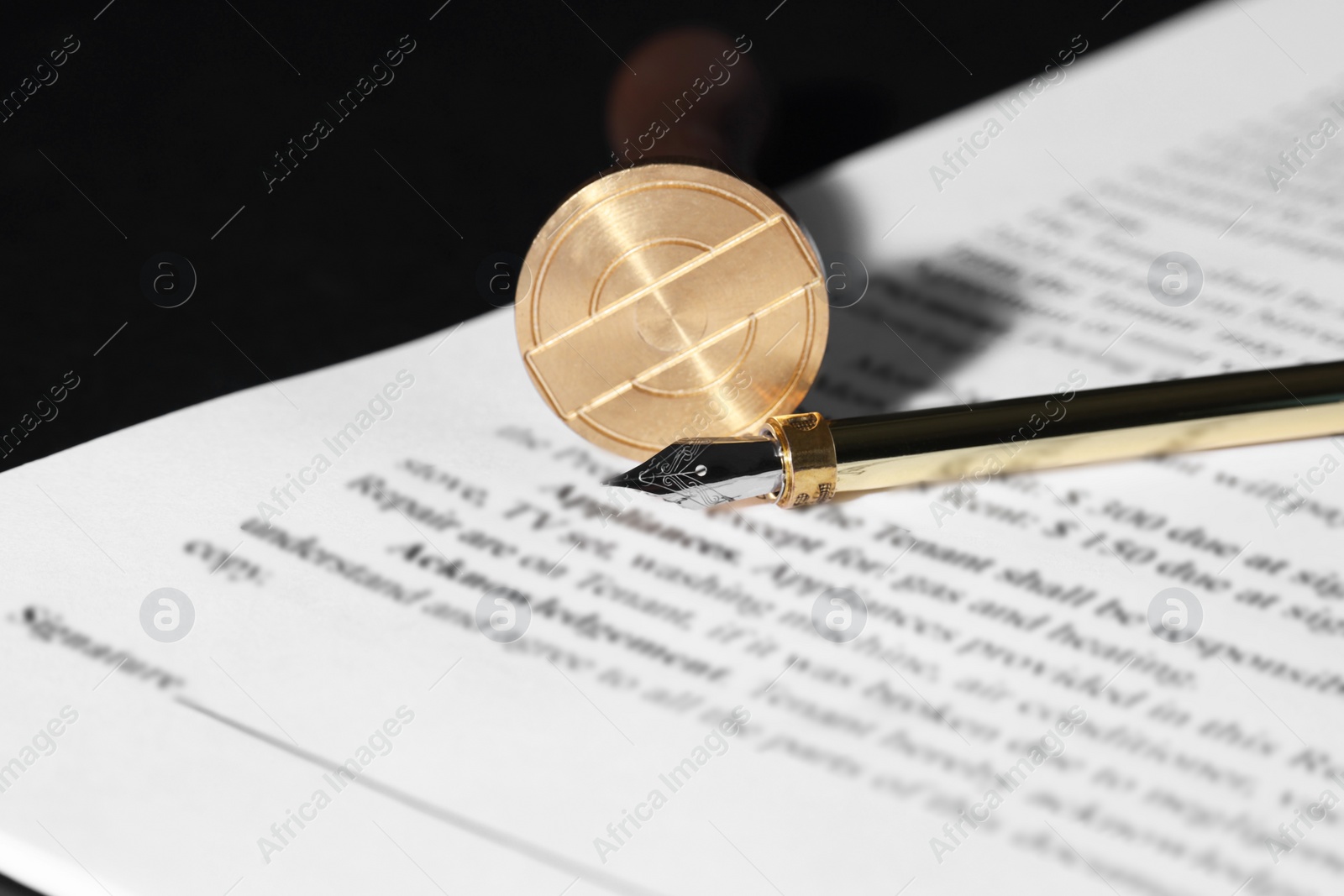 Photo of Fountain pen, wax stamp and paper document on table, closeup. Notary service