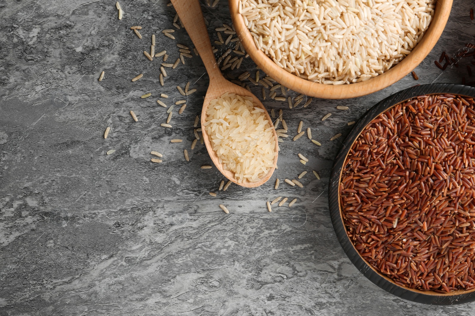 Photo of Flat lay composition with brown and other types of rice on grunge background. Space for text