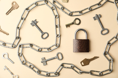 Photo of Steel padlock, keys and chain on beige background, flat lay. Safety concept